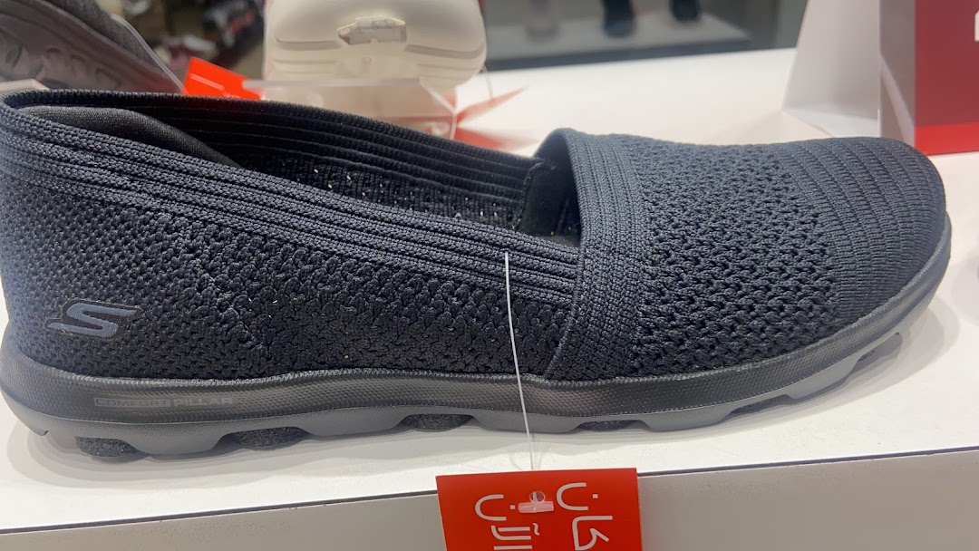 A close-up view of a black Skechers slip-on shoe with a textured knit upper.