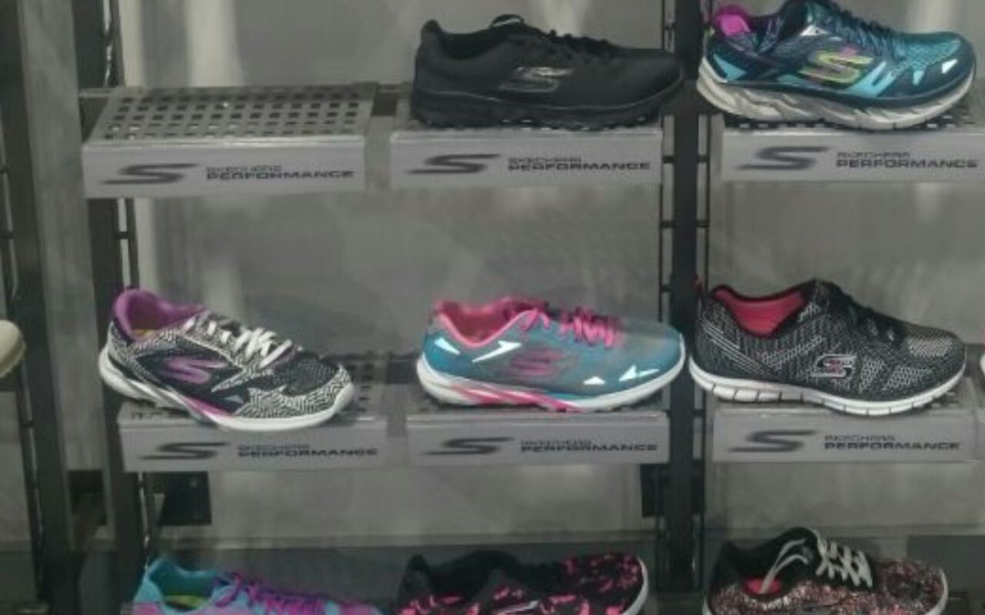 A display of various Skechers athletic shoes on shelves, showcasing different colors and styles.
