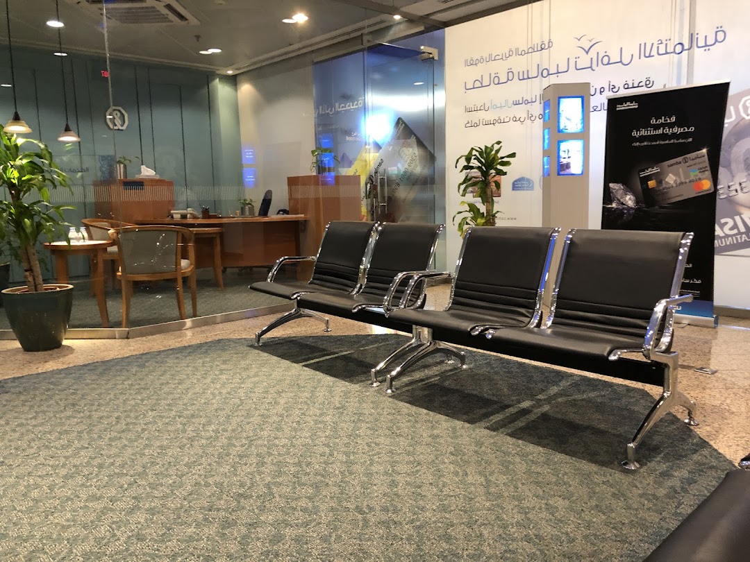 Interior waiting area with black leather chairs, desks, and promotional banners.