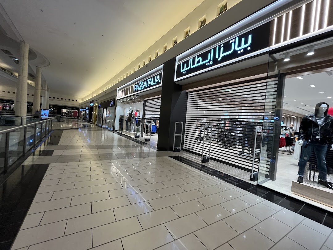 A view of a shopping mall corridor with several storefronts, including Piazza Italia.