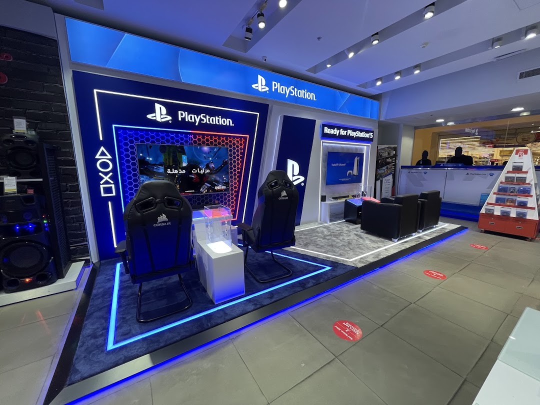 A modern PlayStation gaming setup with chairs, screens, and gaming accessories.