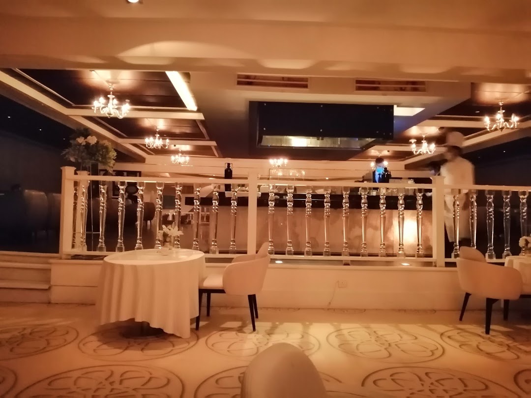 Elegant cafe interior with tables, chairs, and a bar area with staff.