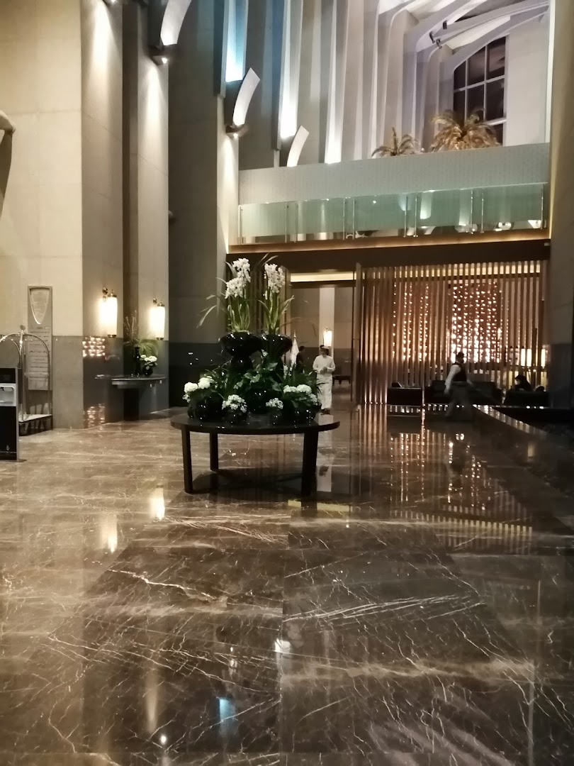Elegant hotel lobby with marble floors, floral arrangements, and modern lighting.