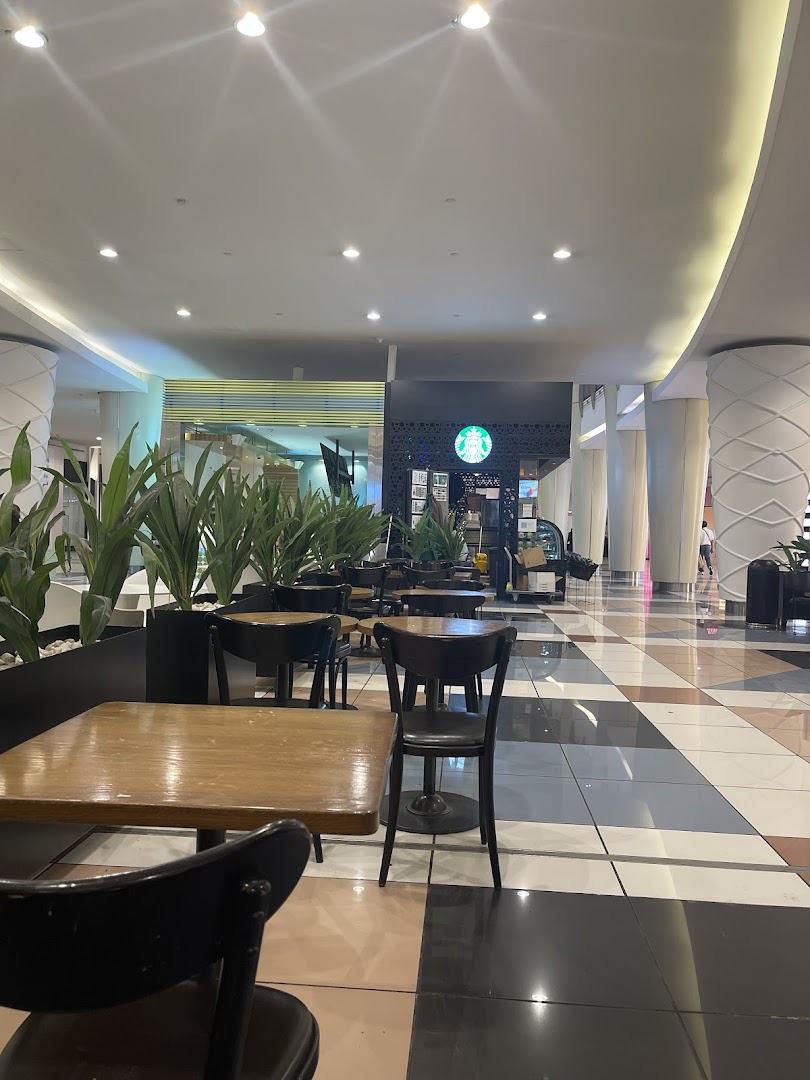 Interior view of a Starbucks coffee shop with seating areas and plants.