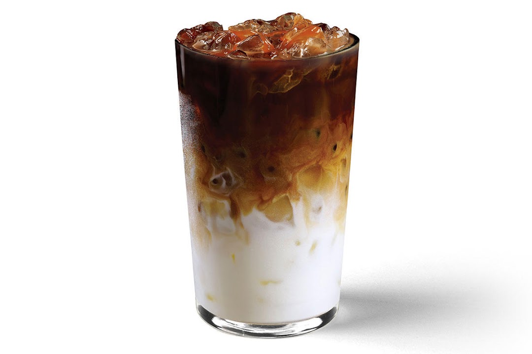A tall glass of iced coffee with layers of milk, coffee, and ice.