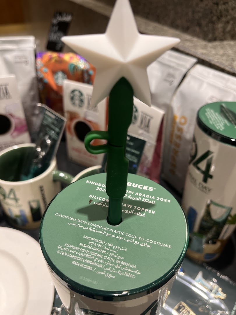 A Starbucks reusable cup lid with a star-shaped straw topper and Arabic text.