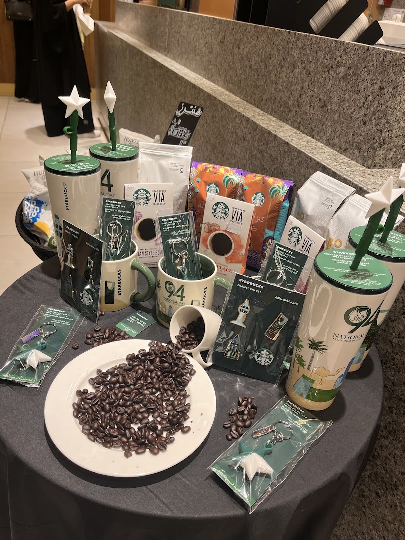 Starbucks merchandise including coffee beans, mugs, VIA coffee, and enamel pin sets.