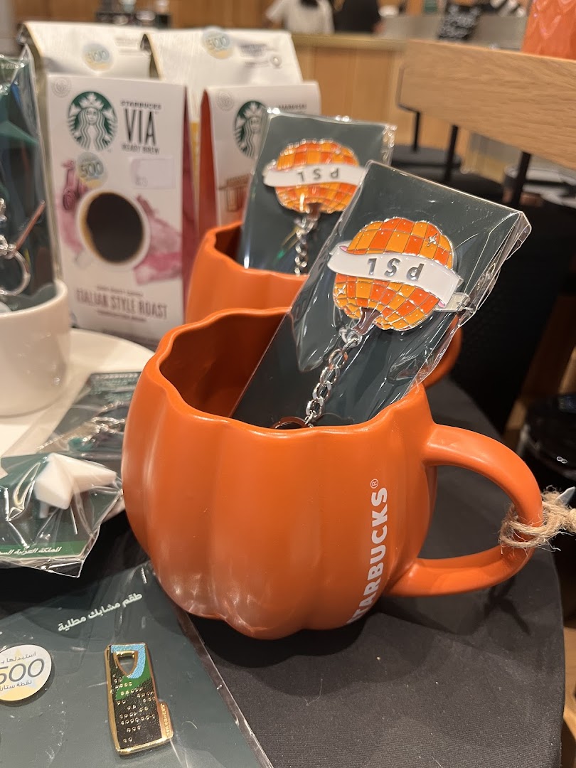 Starbucks pumpkin mug with coffee and keychains displayed.