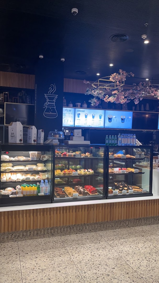 A Starbucks cafe interior showcasing a display of pastries, cakes, and beverages.