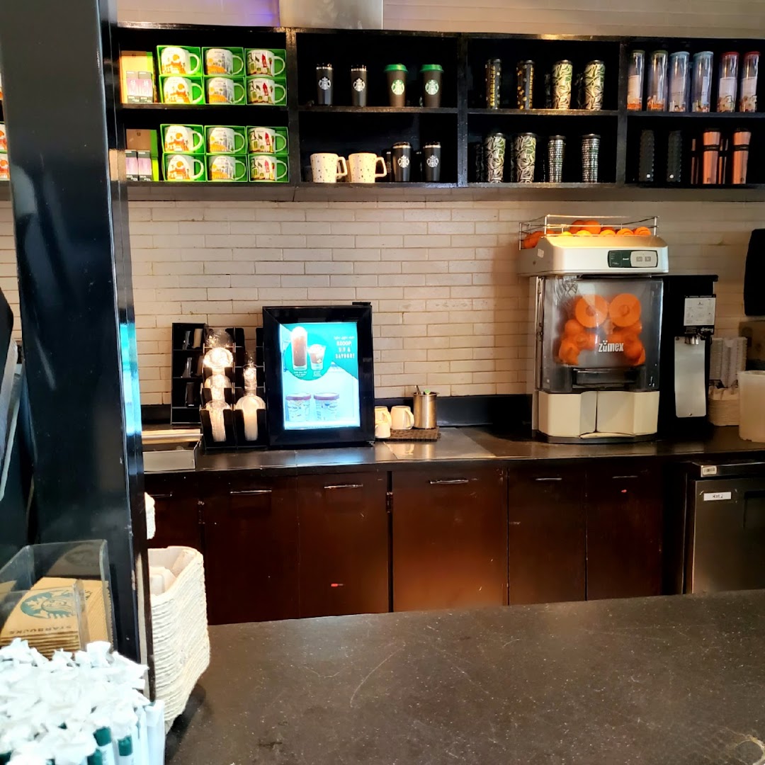 Starbucks counter with merchandise, a digital menu board, and a juice press.
