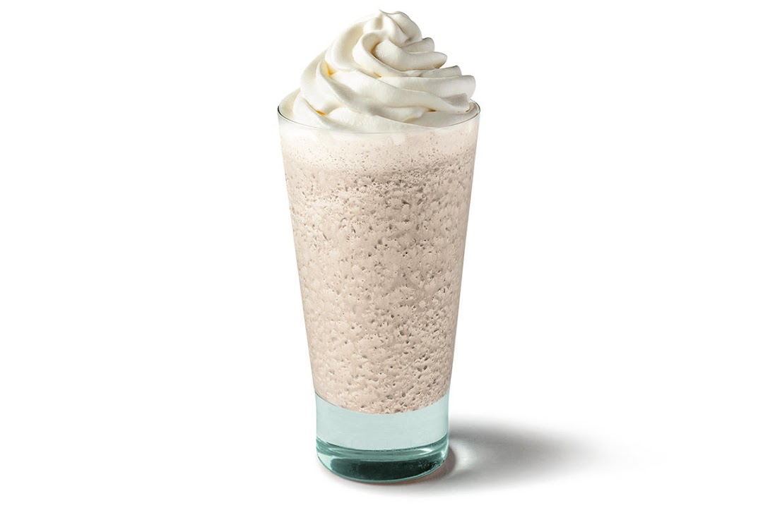 A tall glass of a blended beverage topped with whipped cream.