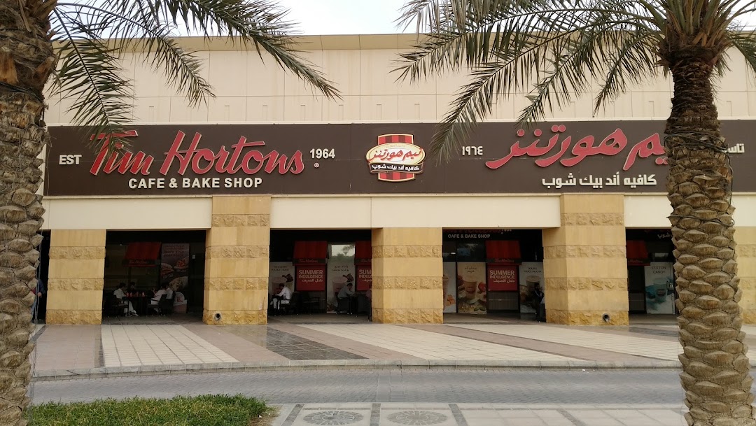 The exterior of a Tim Hortons cafe and bake shop with palm trees in the foreground.
