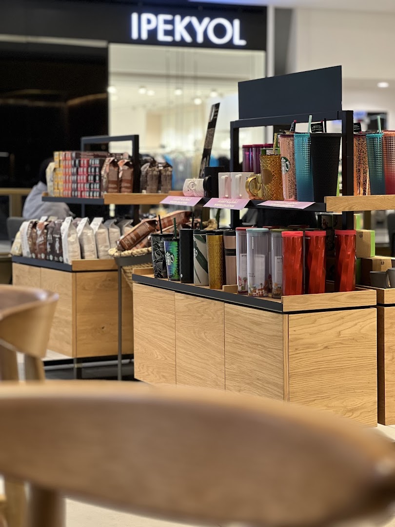 Starbucks shop interior displaying coffee bags and various reusable cups and mugs.