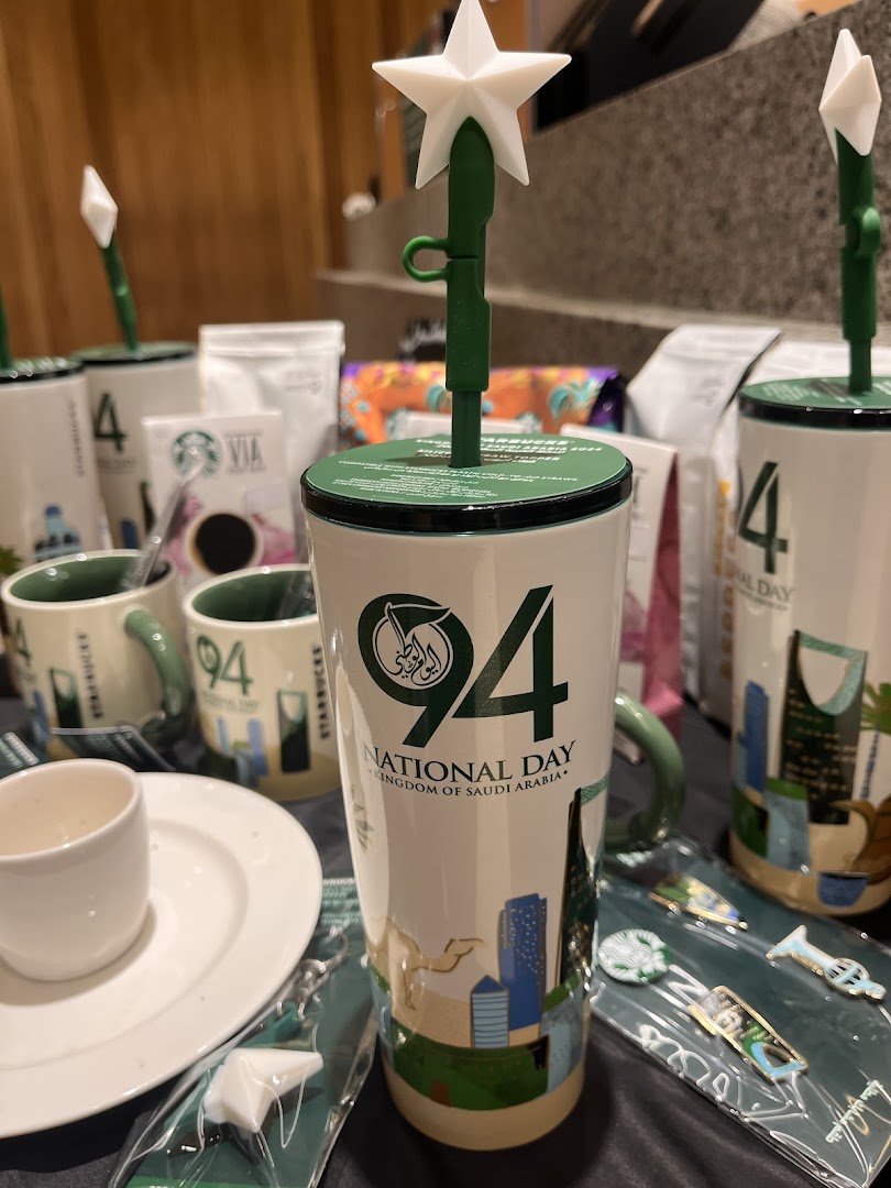 Starbucks merchandise featuring Saudi National Day designs, including cups and keychains.