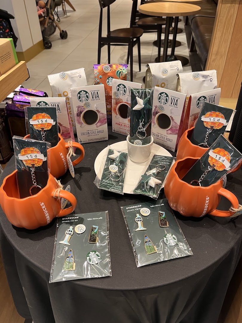 Starbucks display featuring coffee bags, enamel pin sets, and keychains.