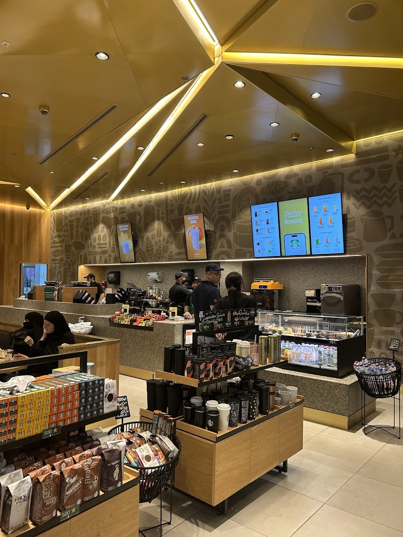 Interior view of a Starbucks coffee shop with customers and merchandise on display.