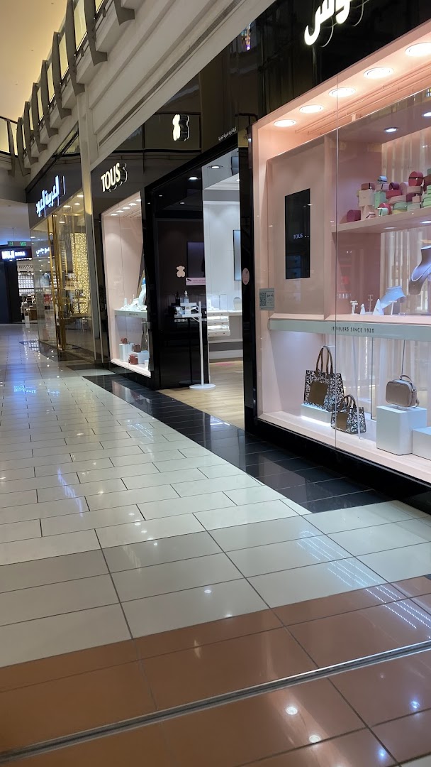 The exterior of a TOUS jewelry store with illuminated displays showcasing handbags and jewelry.