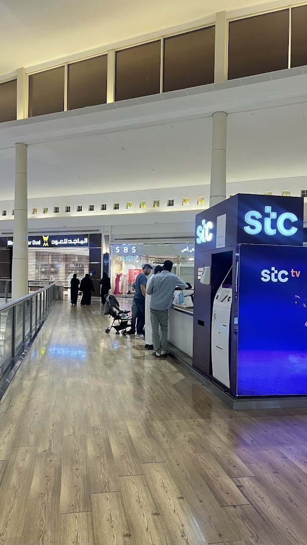 People are interacting at a stc store kiosk in a shopping mall.