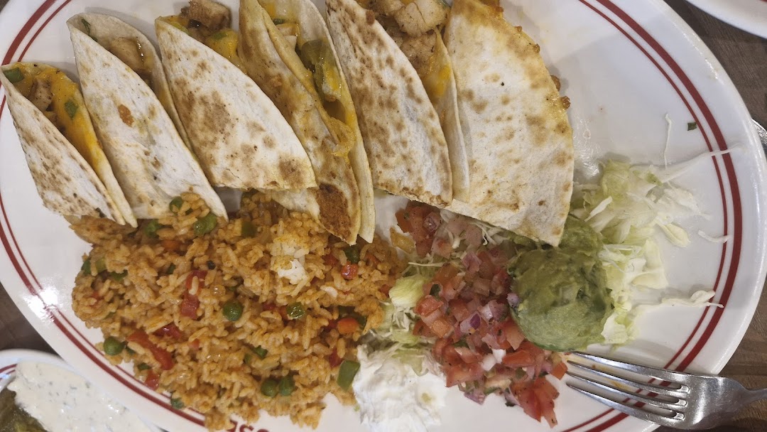A plate of quesadillas with rice, guacamole, pico de gallo, and shredded lettuce.