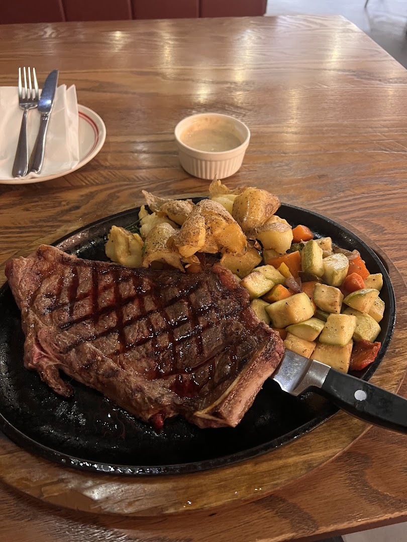 A perfectly grilled steak served with roasted potatoes and mixed vegetables on a wooden table.
