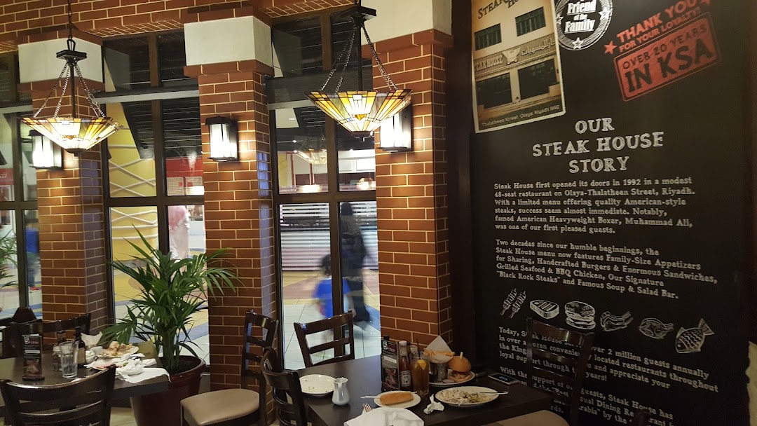 Interior of a Steak House restaurant with brick walls, decorative lighting, and tables set for dining.