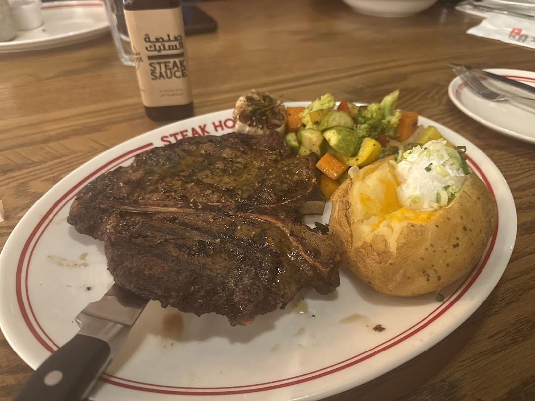 A juicy steak with a baked potato and mixed vegetables on a plate.