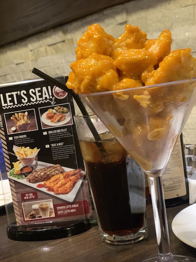 A close-up of a seafood appetizer served in a martini glass with a drink and menu.