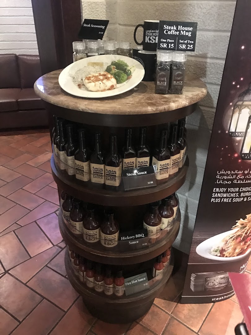 A display of steak sauces, seasonings, and coffee mugs at a Steak House restaurant.