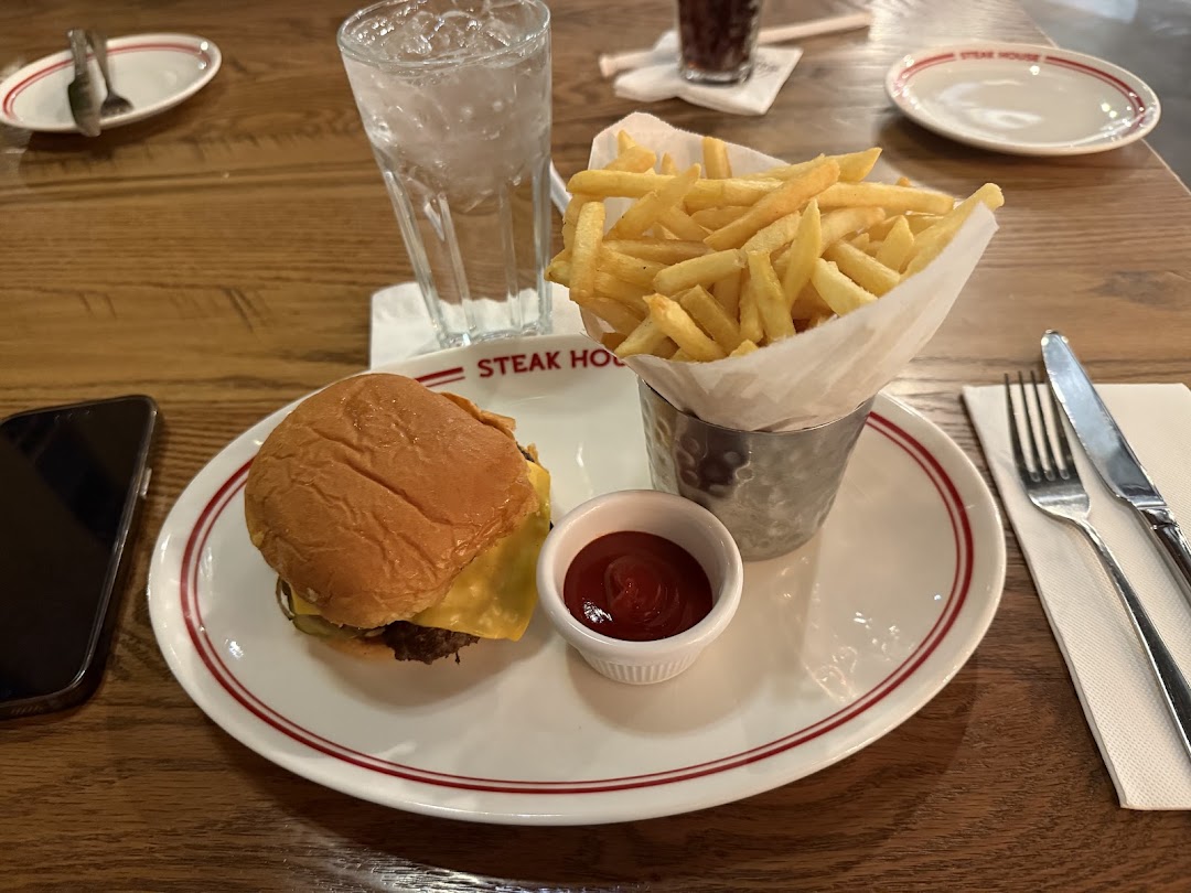 A juicy burger and crispy fries served with ketchup and a drink on a wooden table.