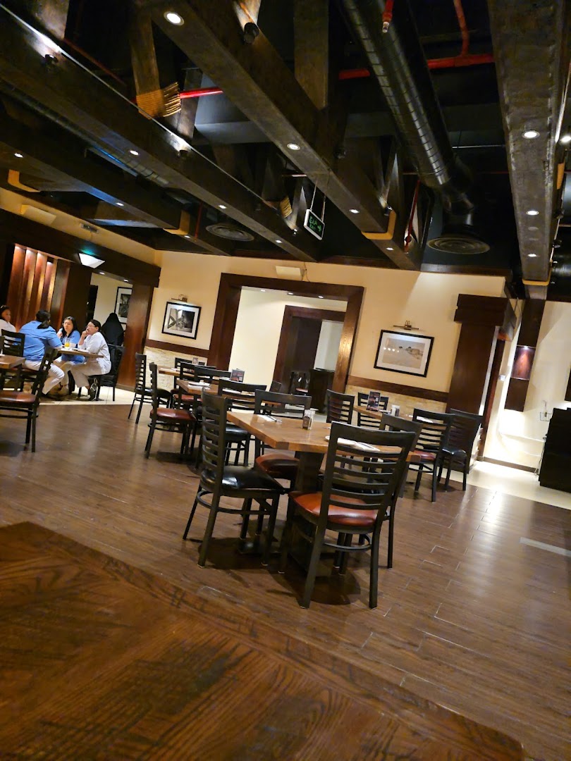 Interior of a steakhouse with wooden tables, chairs, and exposed beams.