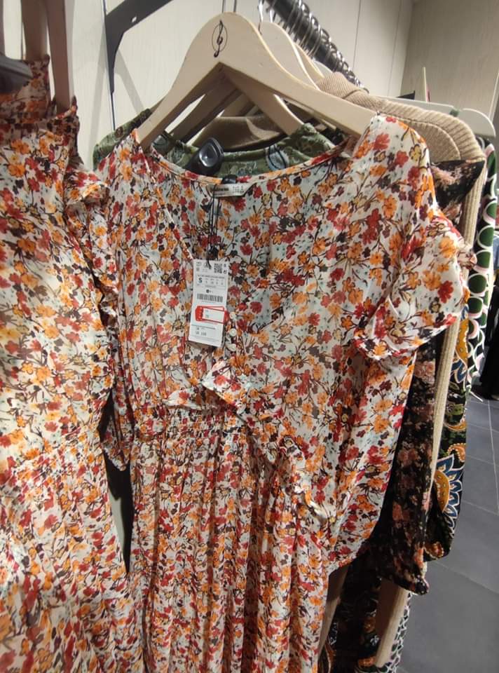 A close-up shot of a floral print dress on a hanger in a clothing store.