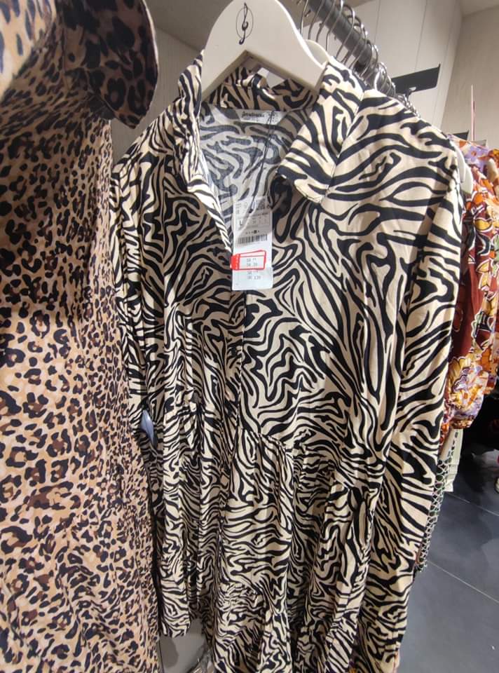 Close-up of two dresses with animal prints, one zebra and one leopard, hanging on hangers.