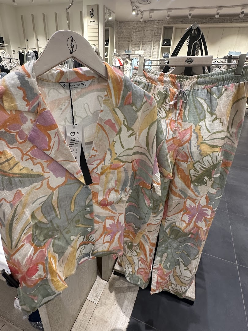 A floral print shirt and matching pants displayed on hangers in a clothing store.