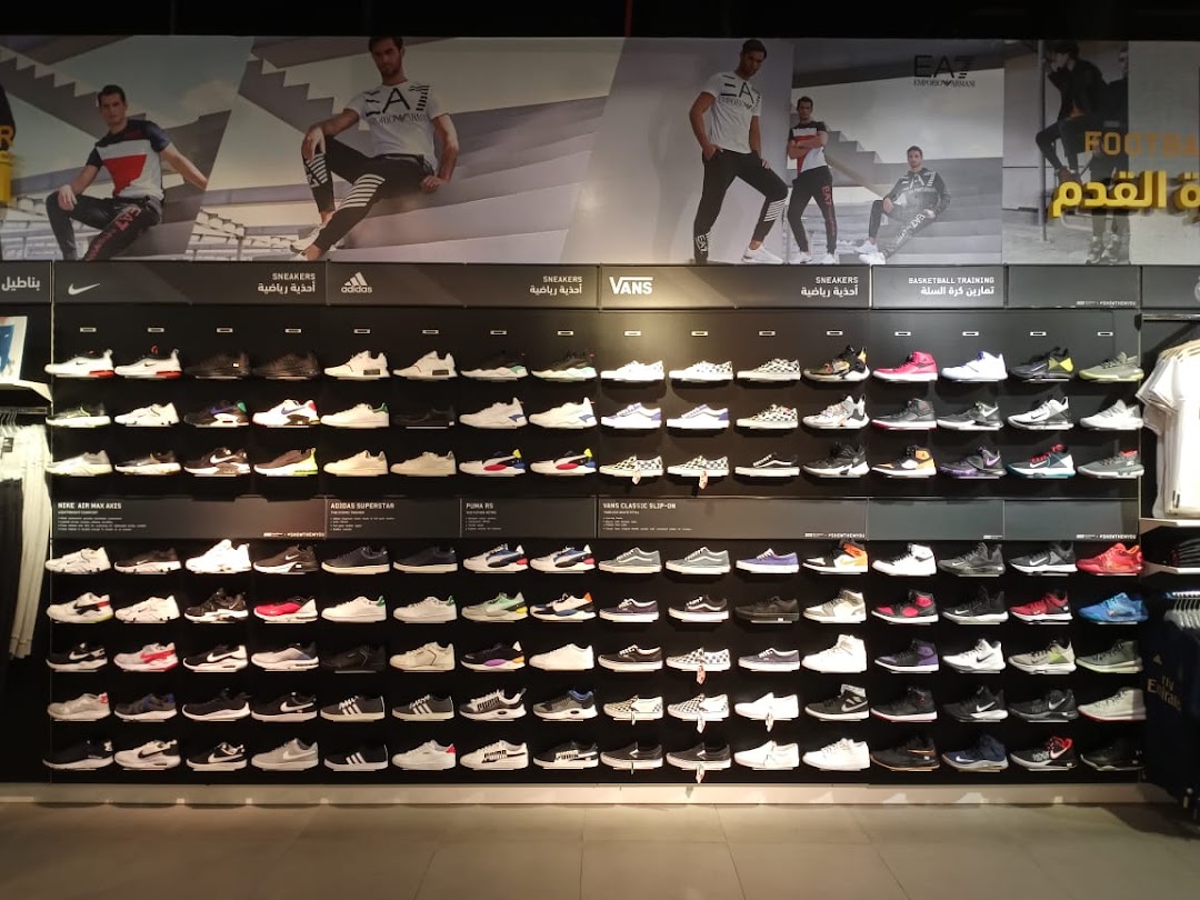 A wide display wall showcasing a large selection of athletic shoes from various brands.