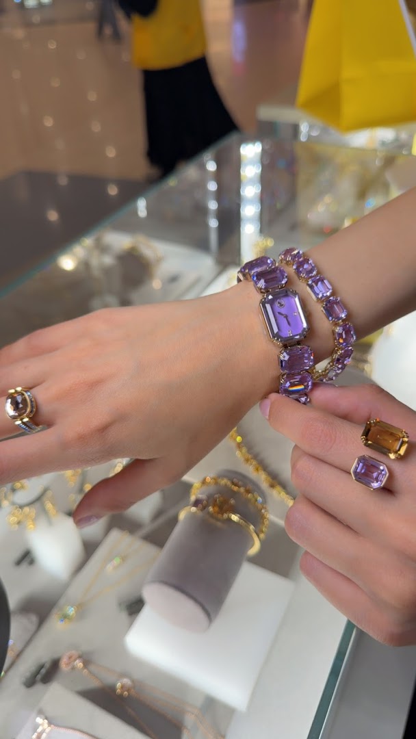 A person wearing a purple gemstone watch and rings, showcasing exquisite jewelry.