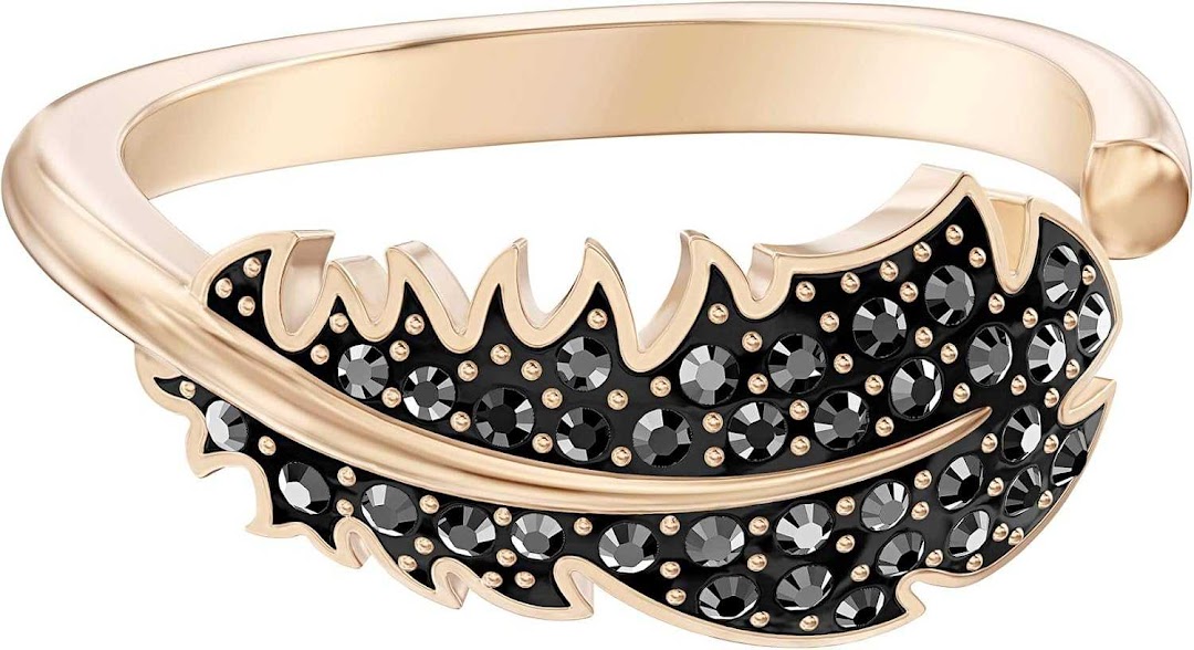 A close-up of a rose gold ring with a black feather design encrusted with black crystals.