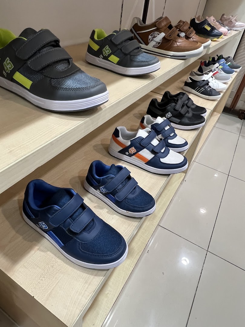 A display of various children's sneakers with velcro straps on shelves.