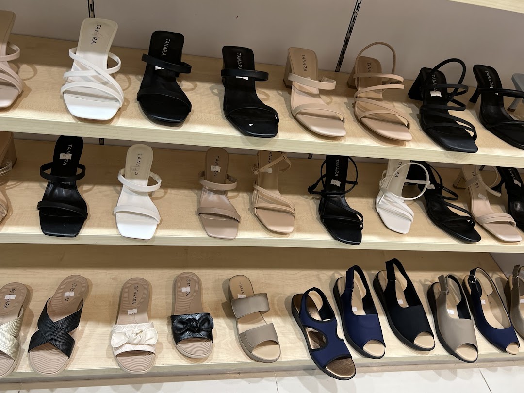 A display of various women's sandals and heels on shelves, in different colors and styles.