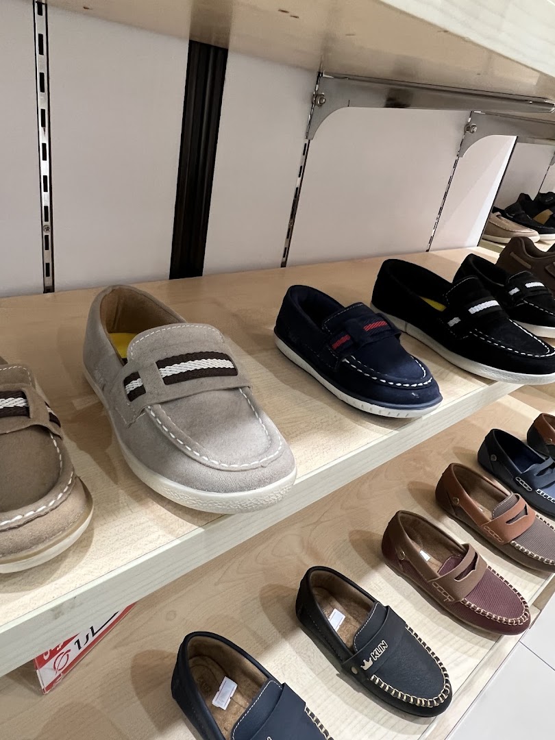 A display of various men's loafers and casual shoes on shelves in a retail store.