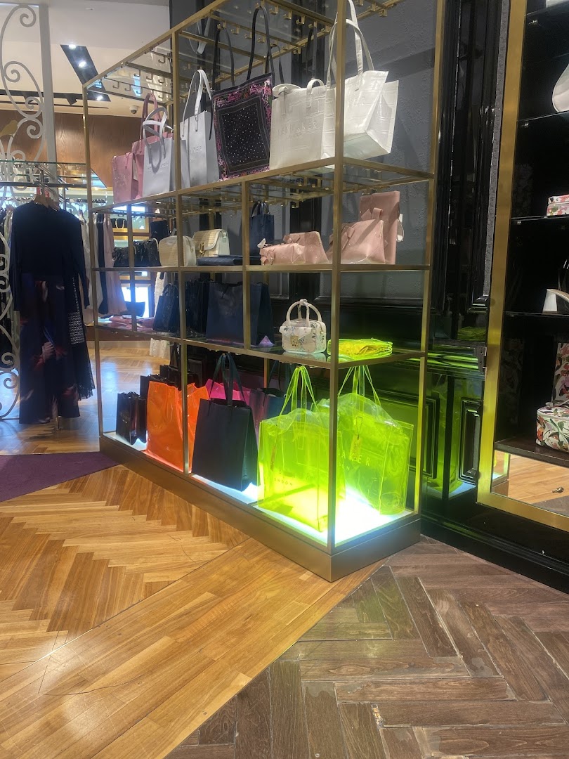 A display of Ted Baker handbags and shopping bags on shelves and illuminated stands.