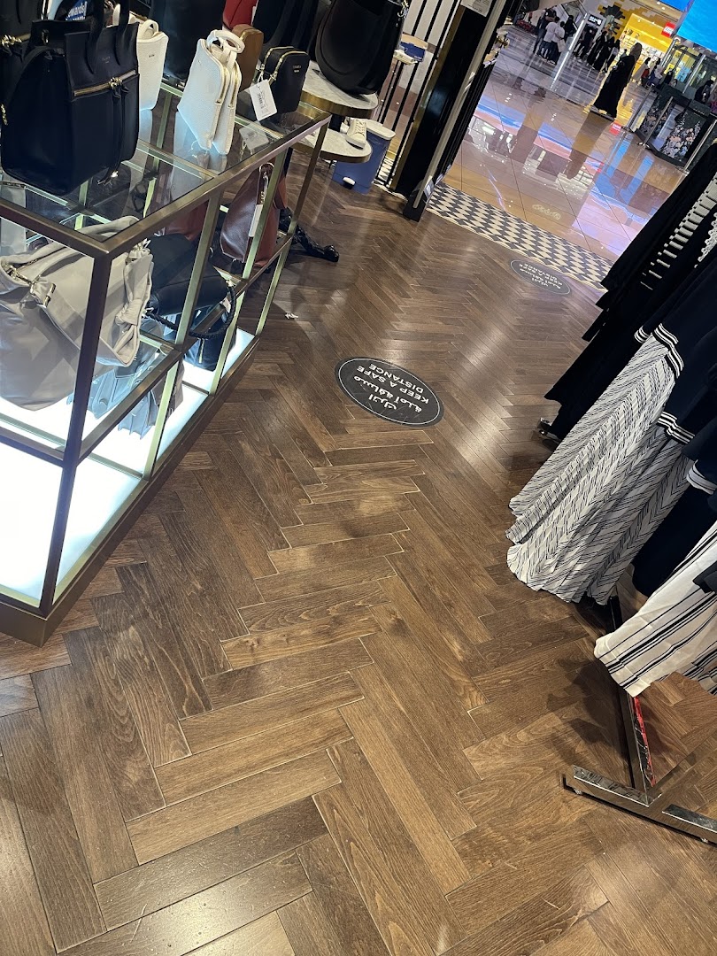 Interior view of a Ted Baker store showcasing handbags and clothing with social distancing markers on the floor.