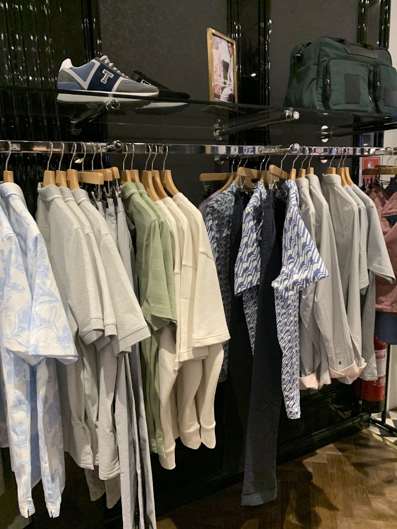 A display of men's clothing, including shirts, trousers, and a pair of sneakers, at Ted Baker.