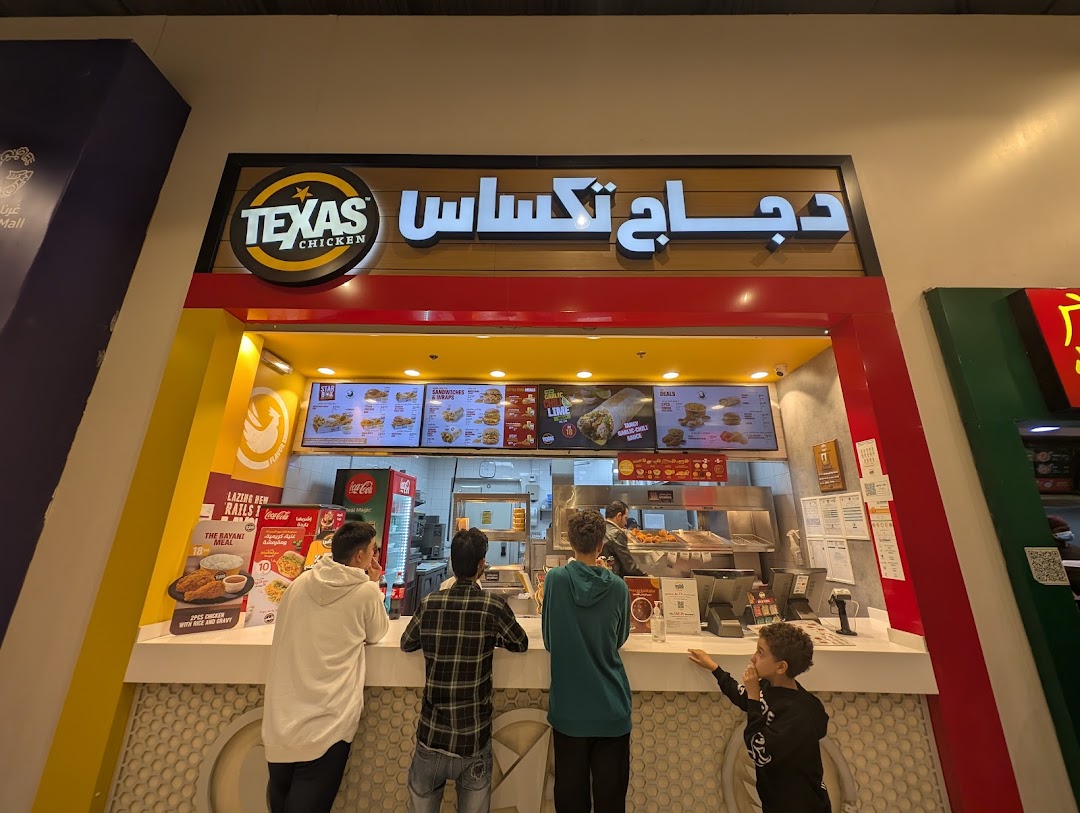 People ordering at the Texas Chicken counter with menu boards above.
