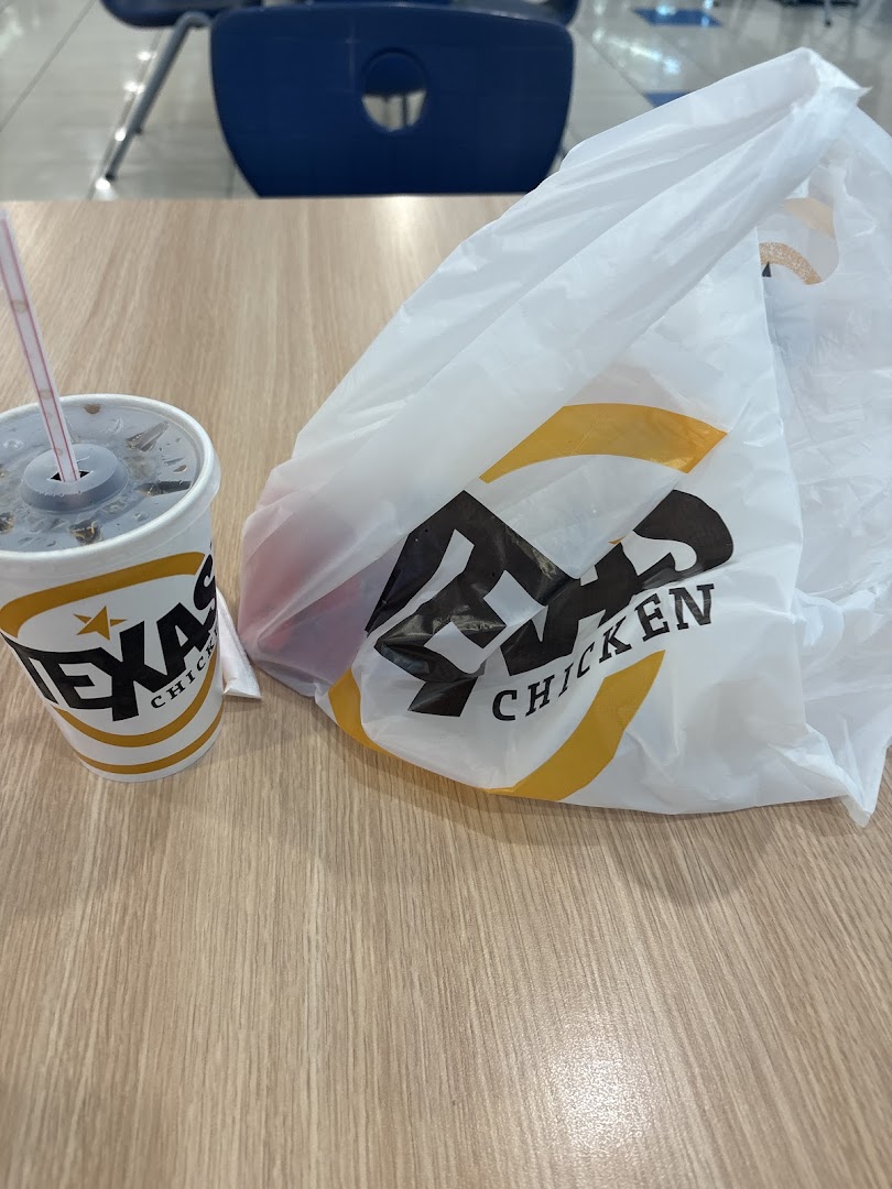 A Texas Chicken branded cup and takeaway bag sit on a wooden table.