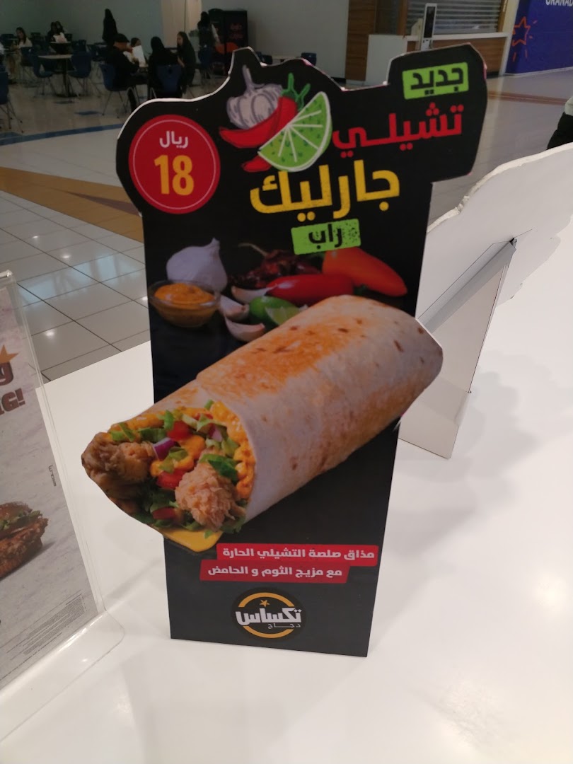 A promotional stand for Texas Chicken featuring a spicy garlic wrap with chili, lime, and garlic.