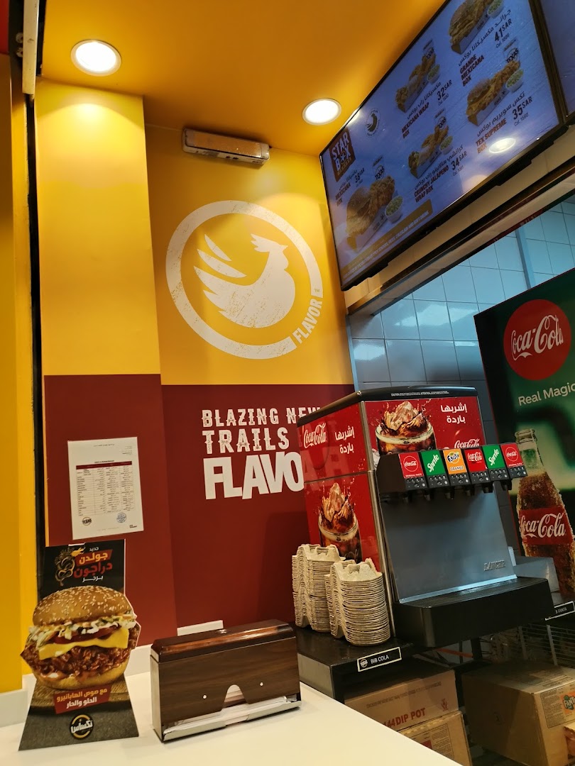 Interior view of Texas Chicken with a menu board, drink dispenser, and burger display.