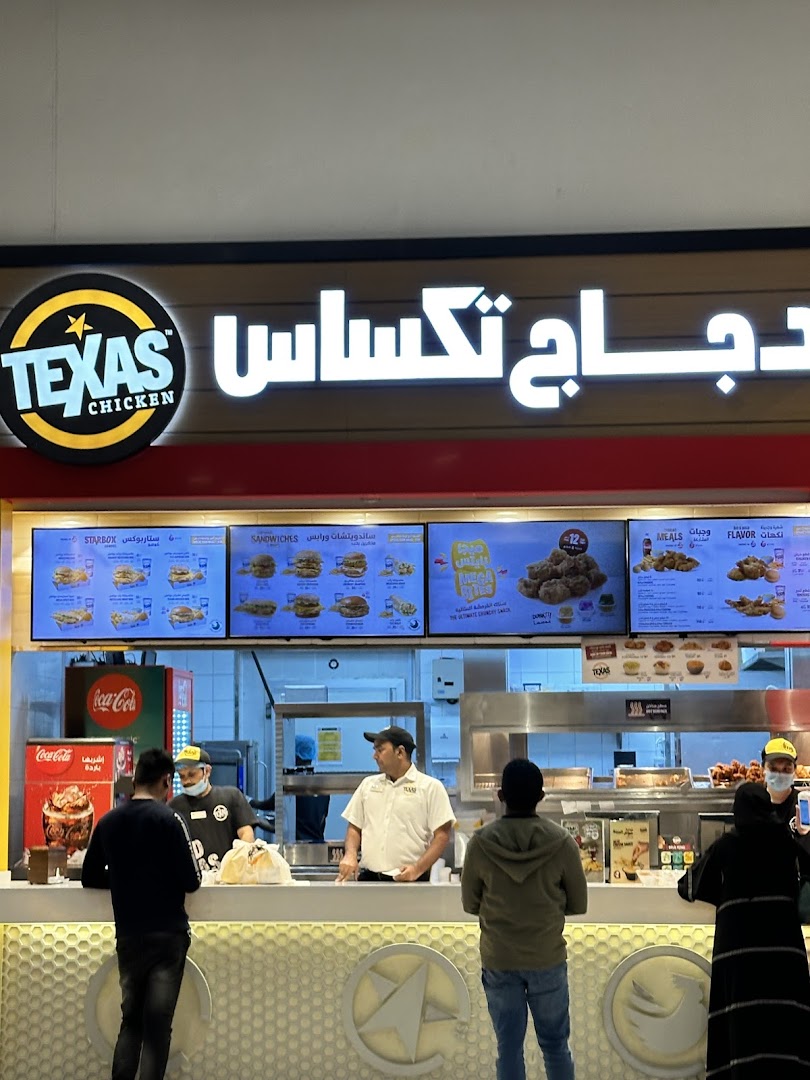 Customers ordering at the Texas Chicken counter with digital menus displaying food items.