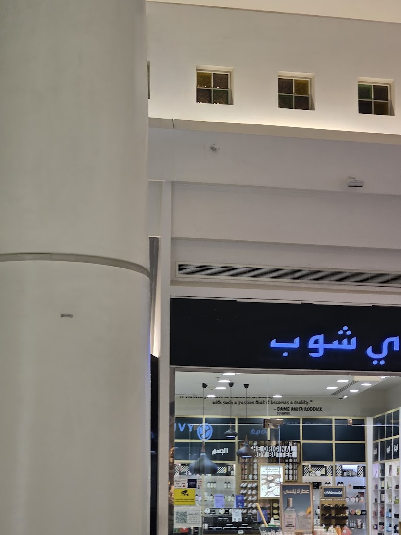 The Body Shop storefront with its name in Arabic and English, displaying products inside.