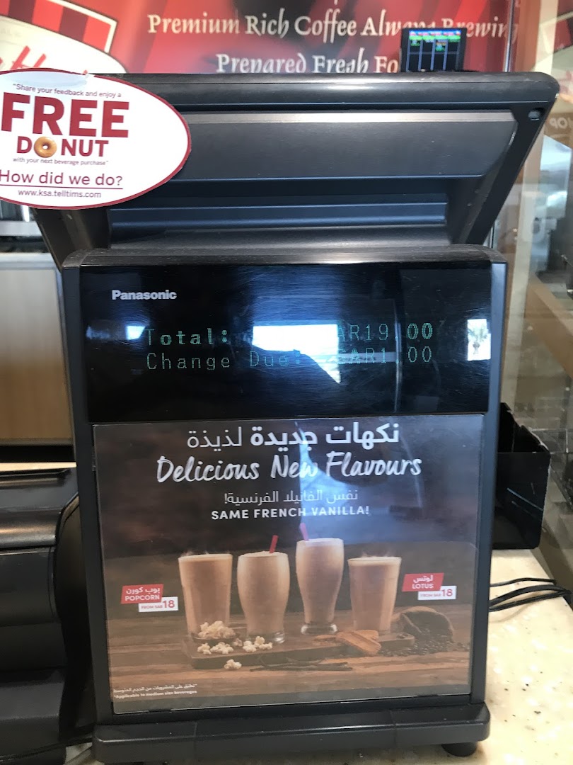 A Tim Hortons machine displays a transaction total and advertises new flavors with drinks and popcorn.