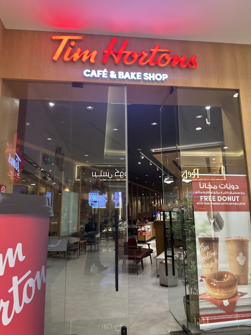 The entrance to a Tim Hortons cafe and bake shop with a large red cup outside.